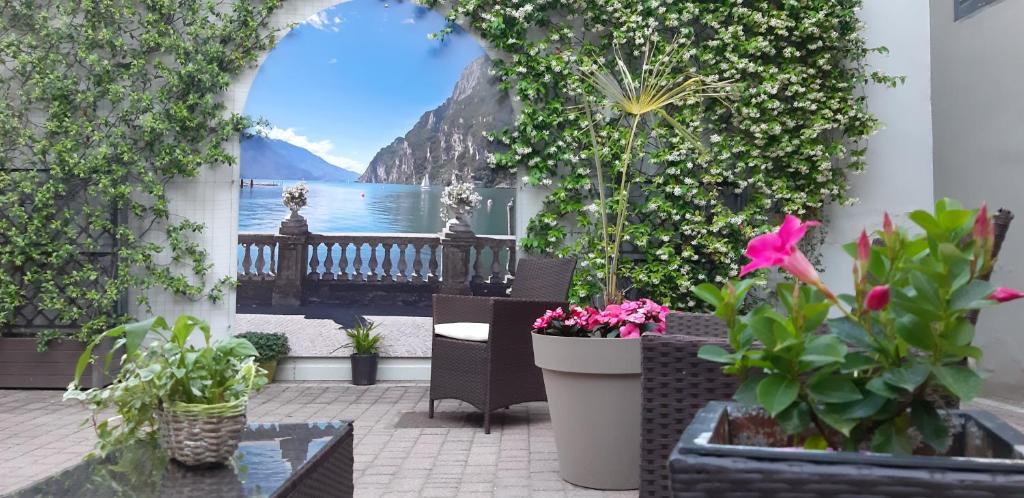 eine Terrasse mit Pflanzen und Blick auf das Wasser in der Unterkunft Bella Villa Apartments in Riva del Garda
