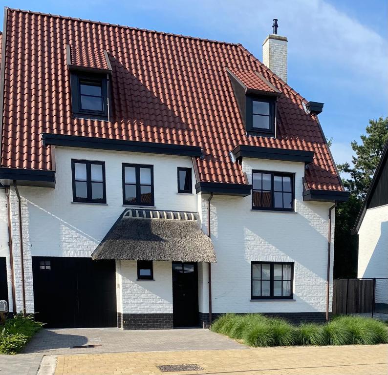 een wit huis met een rood dak bij Les Cigognes in Knokke