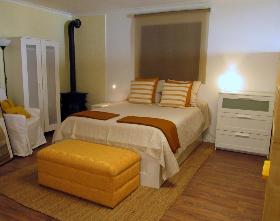 a bedroom with a large bed and a yellow ottoman at Go PT - Private challet with swimming pool and garden in Parede