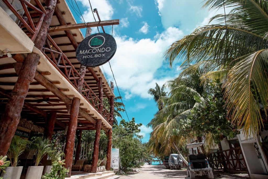 a sign for a restaurant on a street with palm trees at Hotel Macondito Holbox in Holbox Island