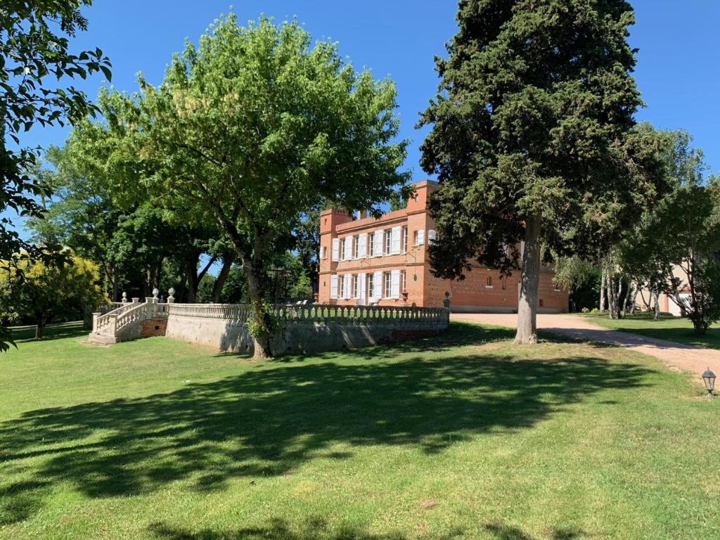 Saint-LysにあるChâteau Ratouの木々と芝生の公園内の大きな建物