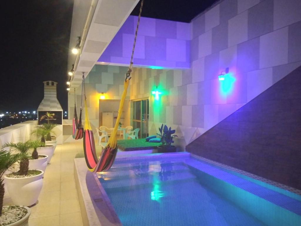 einen Pool mit Hängematte in einem Gebäude in der Nacht in der Unterkunft luxuosa cobertura praia do futuro 1002 in Fortaleza
