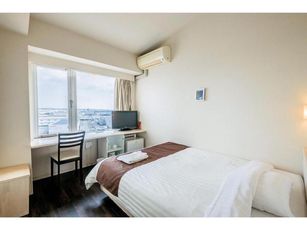 1 dormitorio con cama, escritorio y ventana en HOTEL GranView Garden OKINAWA - Vacation STAY 44967v, en Tomigusuku