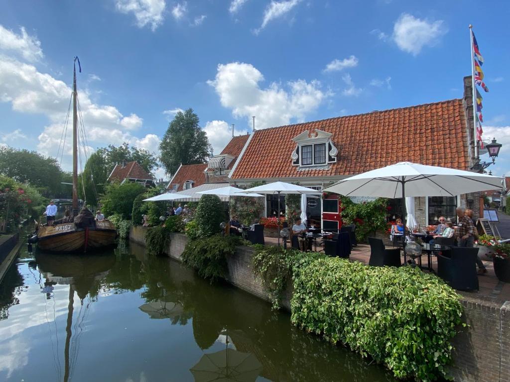 ein Restaurant mit Tischen und Sonnenschirmen neben einem Fluss in der Unterkunft Hotel & Restaurant De Fortuna in Edam