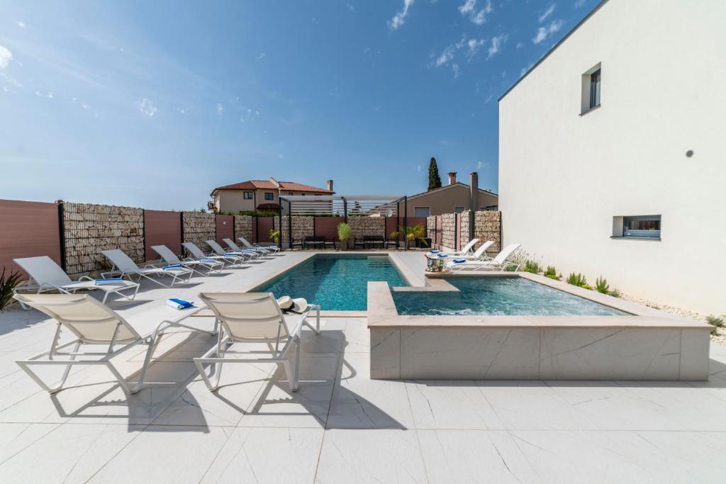patio z krzesłami i basenem w obiekcie PINNA RESIDENCE - Datul w Puli