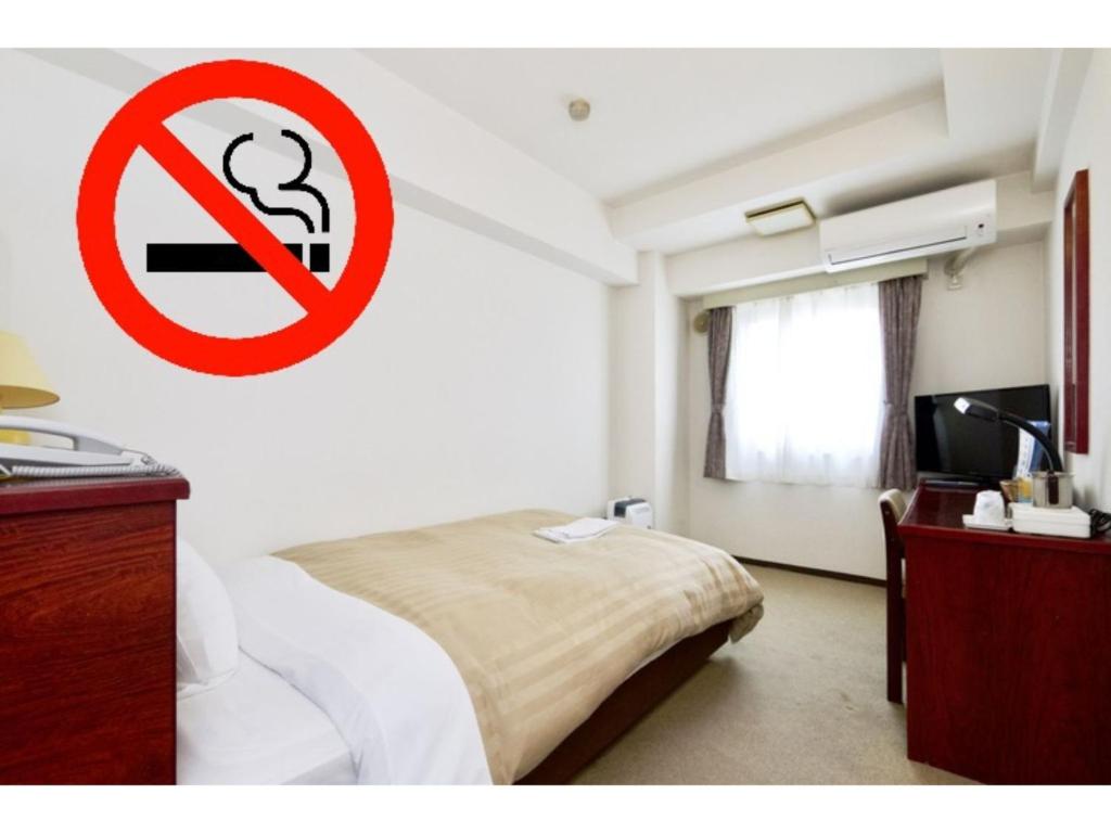 Zimmer mit einem Bett mit einem Nichtraucherschild an der Wand in der Unterkunft Sky Heart Hotel Koiwa - Vacation STAY 49094v in Tokio