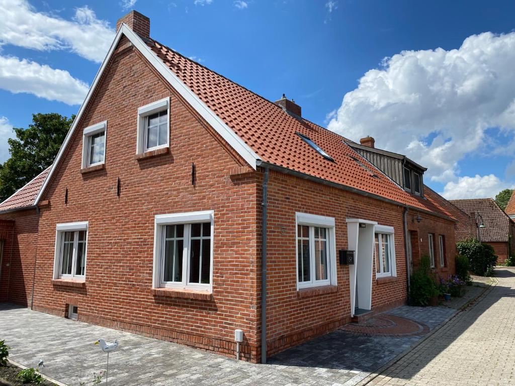 dom z czerwonej cegły z białymi oknami na ulicy w obiekcie Pilsumer Lohne Huus w mieście Krummhörn