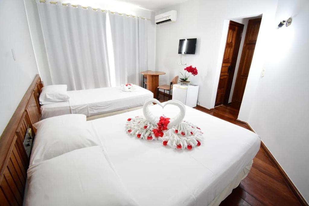 a hotel room with two beds with white sheets and two hearts at Hotel Jalim in Caldas Novas
