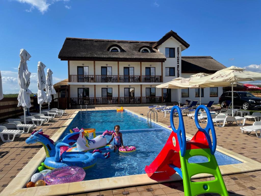 un niño está jugando en la piscina de un complejo en Pensiunea Belvedere Murighiol, en Murighiol