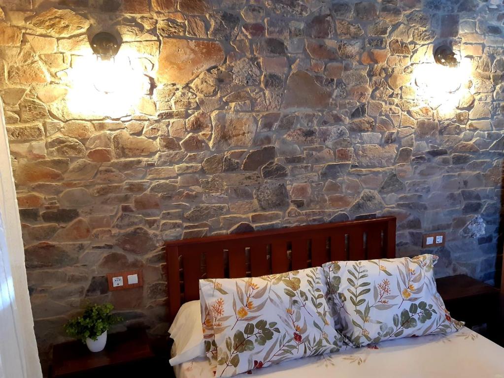 1 dormitorio con pared de piedra, 1 cama y 2 luces en Apartamentos Callampa, en Torrejón el Rubio
