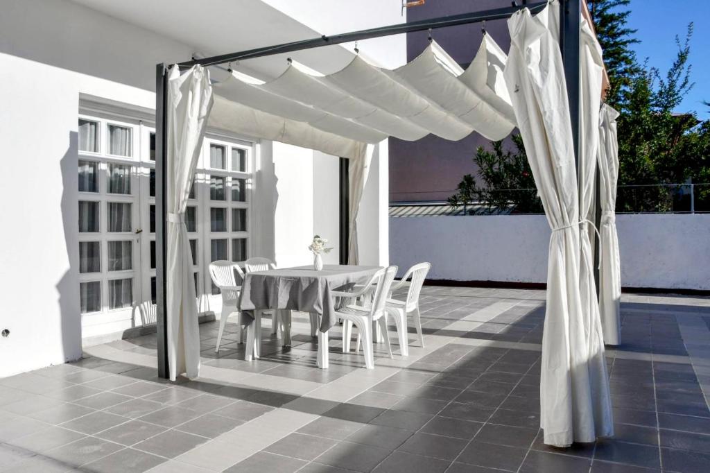 eine weiße Pergola auf einer Terrasse mit einem Tisch und Stühlen in der Unterkunft Sea Star Apartments in Pješčana Uvala
