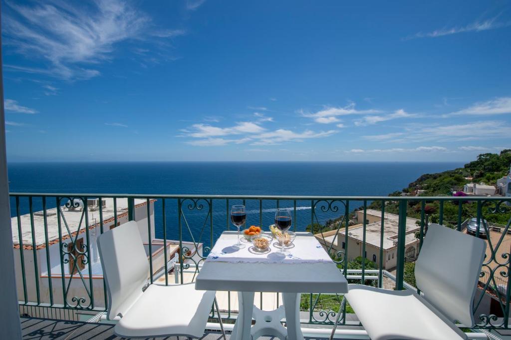 einen Balkon mit einem Tisch, Stühlen und Meerblick in der Unterkunft Moressa Little in Praiano
