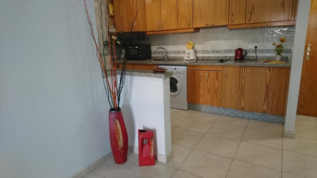 una cucina con un vaso rosso con bastoncini di Apartamento del sol a Orihuela Costa