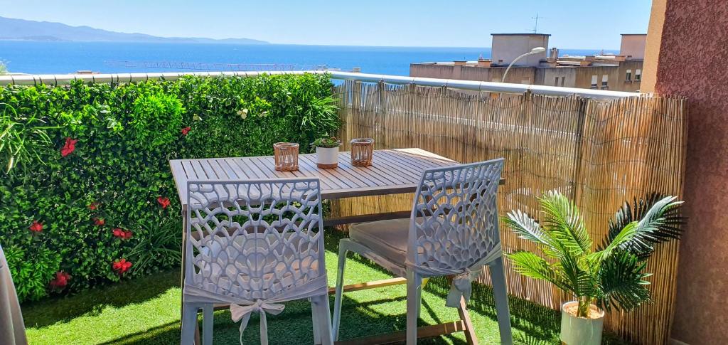 a table and chairs on a balcony with the ocean at Appartement Ajaccio vue mer panoramique in Ajaccio
