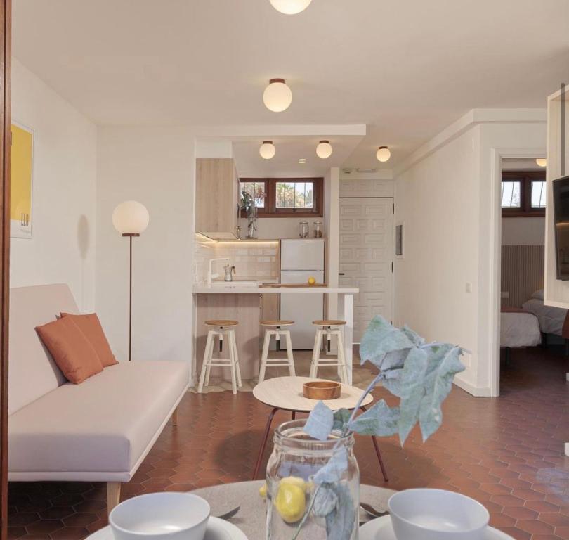Una sala de estar con un sofá blanco y una cocina. en Alsol Las Orquídeas, en Playa del Inglés
