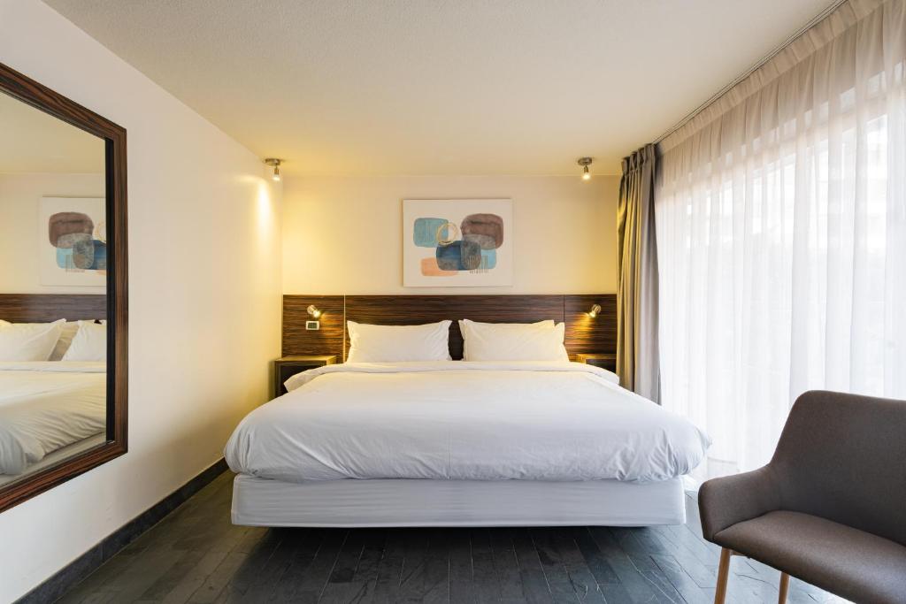 1 dormitorio con 1 cama blanca grande y espejo en Tribeca Silver - Ex habitación de hotel sin cocina, en Santiago