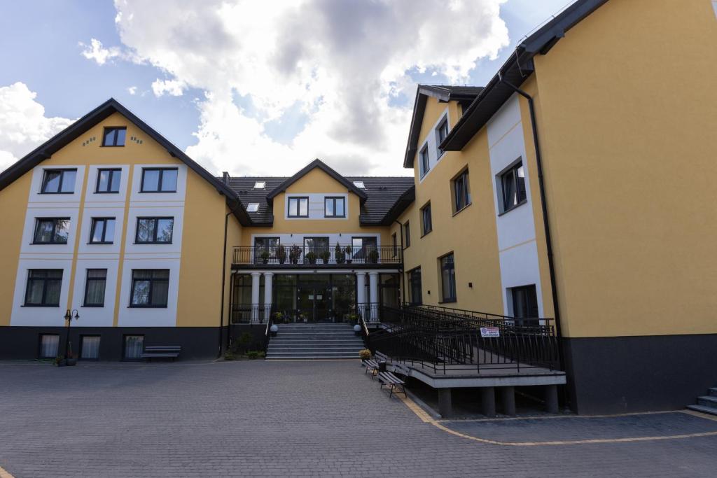 Large yellow building with multiple windows and entrance stairs.