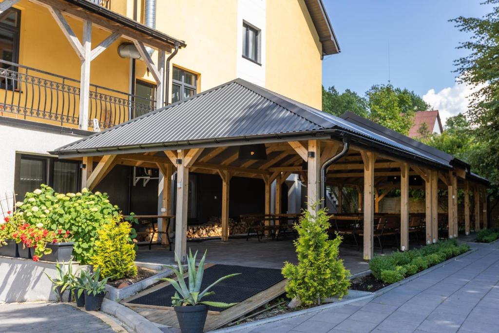 Outdoor pavilion with wooden beams surrounded by greenery.