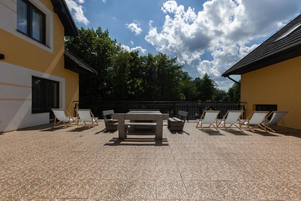 Spacious outdoor patio with lounge chairs and table under a cloudy sky.