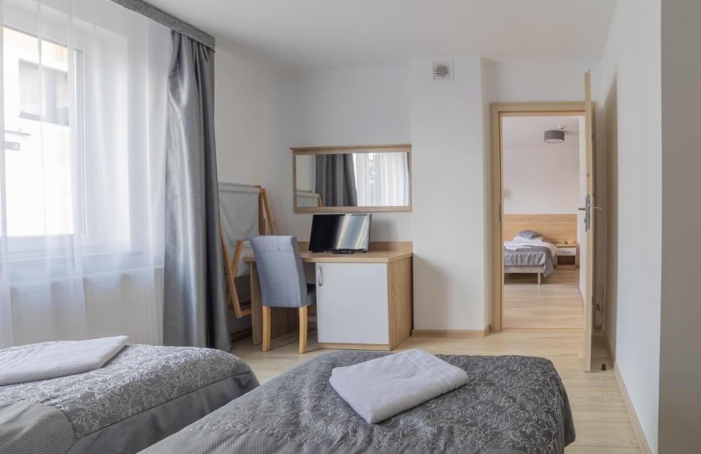 Room with two beds, desk, chair, and open door leading to another room.