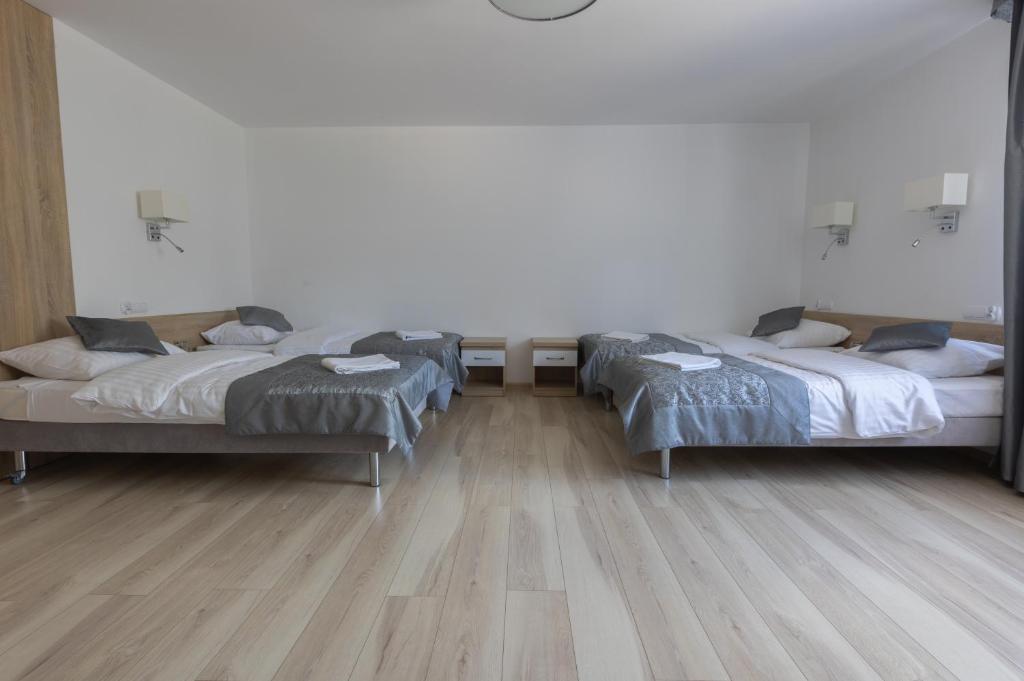 Spacious room with two beds, wooden floor, and minimalist decor.