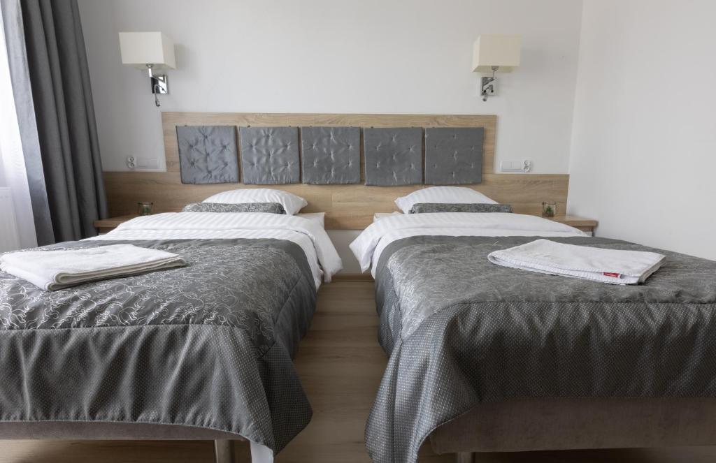 Close-up of two single beds with gray bedding in a well-lit room.