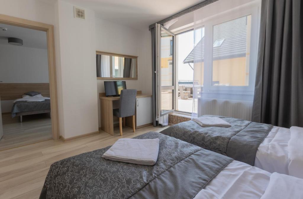 Room with twin beds, desk, and open balcony door.