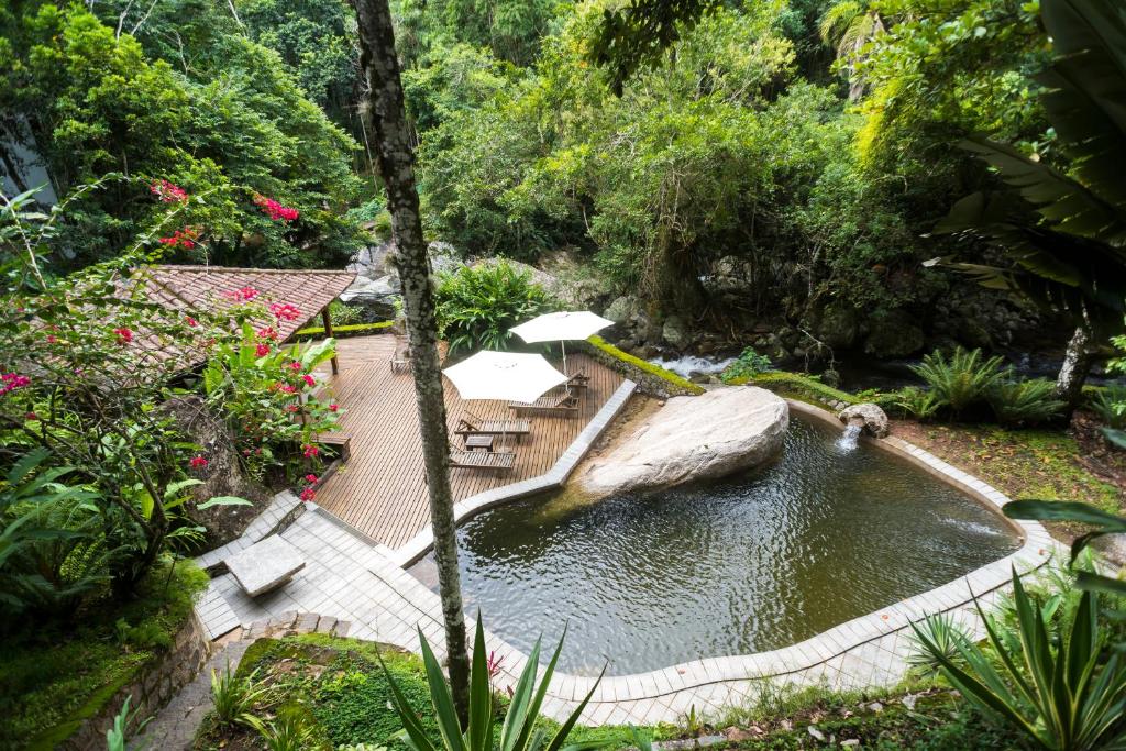 a pond in a garden with umbrellas and trees at Guest House Ilha Splendor in Ilhabela