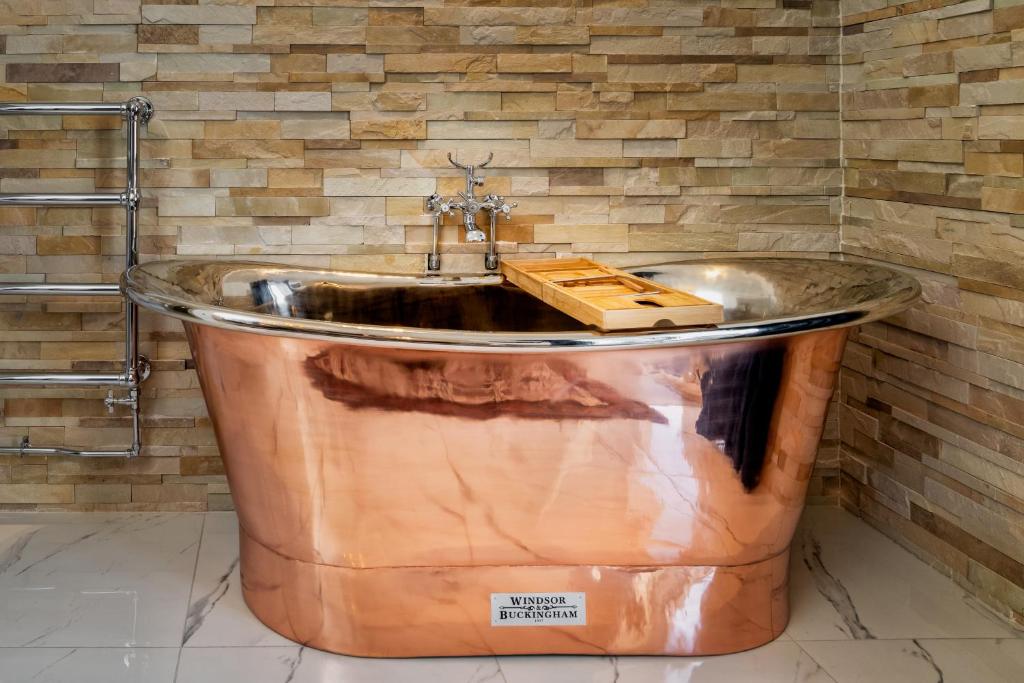 baño con lavabo y bañera grande de cobre. en Relax in Super Size Copper Tub - 2 bedroom villa en Inverness