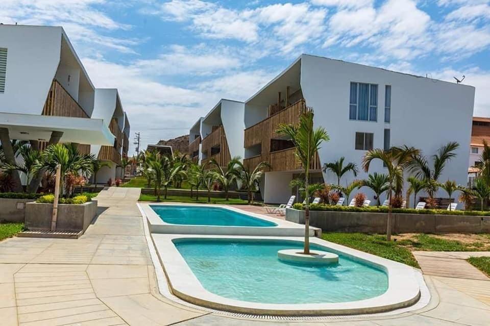 a villa with a swimming pool in front of a building at Palmeras de bocapan in Bocapán