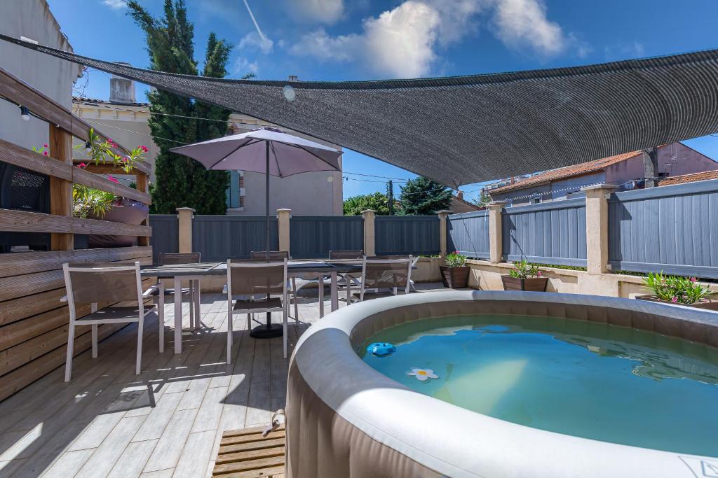 un patio con piscina, mesa y sombrilla en Appartement Domloc, en Carcassonne