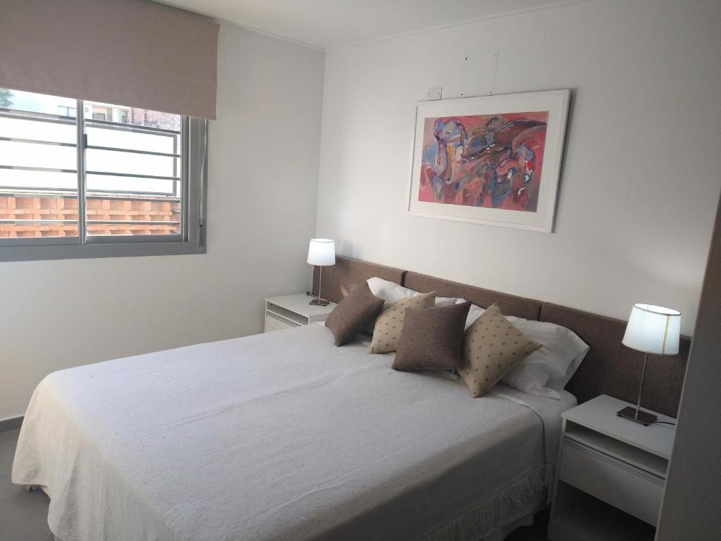Dormitorio blanco con cama blanca y almohadas en Habitat Plaza en Córdoba
