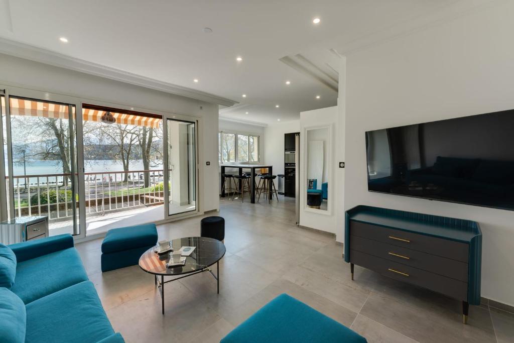 a living room with a blue couch and a tv at Swan Lake - Design apartment facing Lake Annecy in Annecy