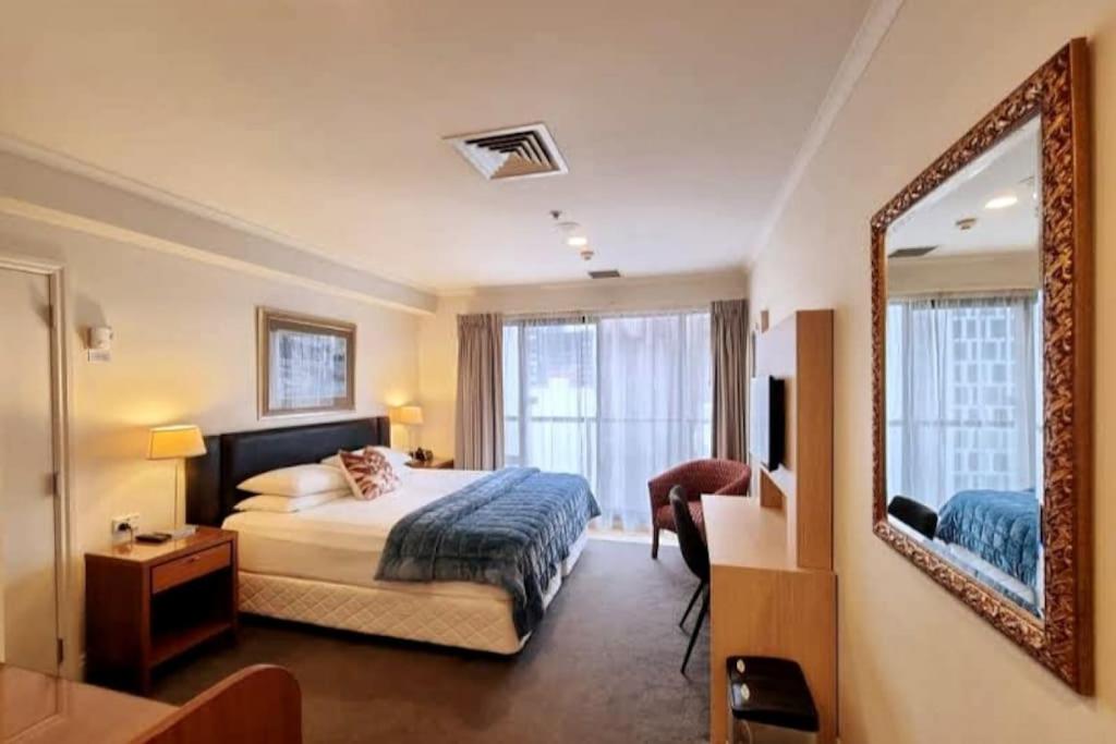 una habitación de hotel con una cama y un espejo en Metroview Studio in CBD with Air-con, Pool and Gym, en Auckland