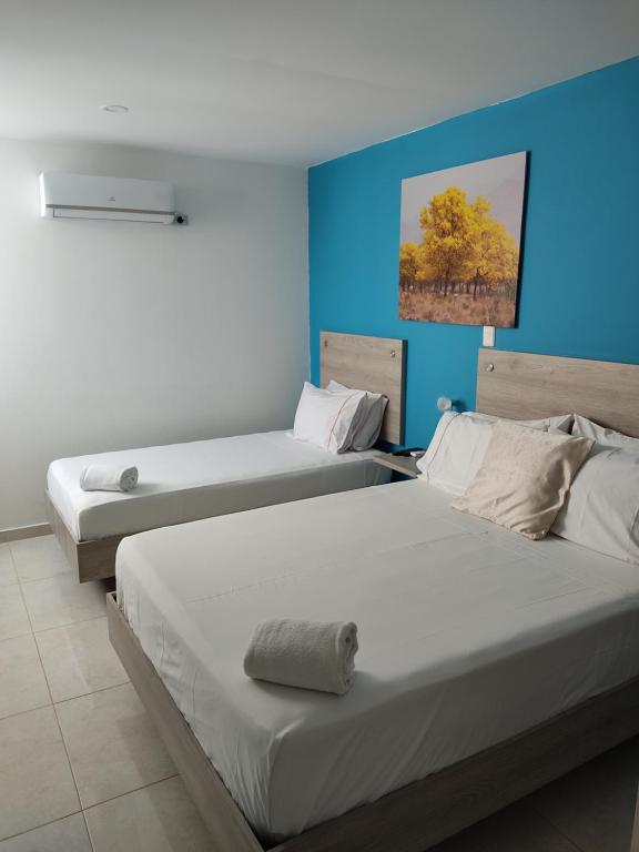 two beds in a room with blue walls at Escala Hotel in Valledupar