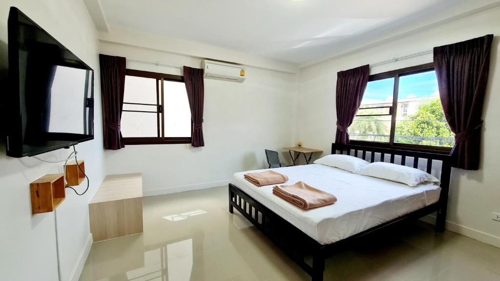 um quarto com uma cama e uma televisão de ecrã plano em TP House@Naka em Cidade Phuket