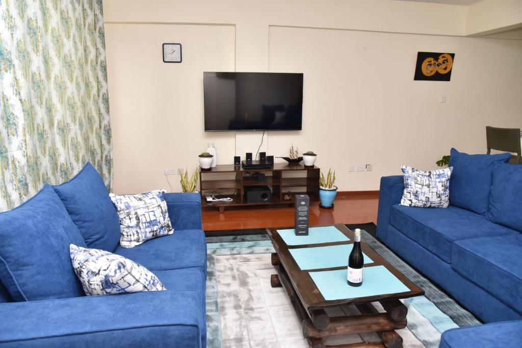 a living room with blue couches and a tv at Karen View Palace Apartments in Nairobi
