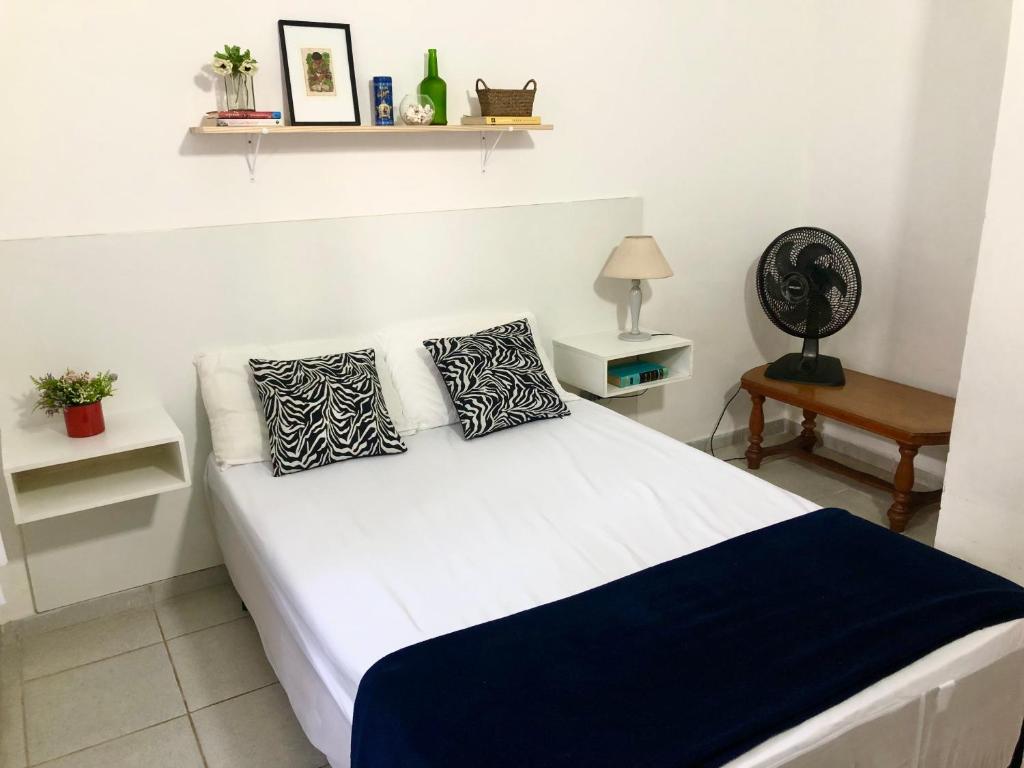 uma cama branca com duas almofadas num quarto em Casa com ótima localização em Piracicaba