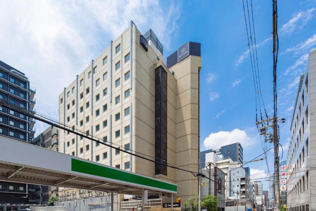 ein hohes Gebäude mit einem Schild davor in der Unterkunft The OneFive Osaka Sakaisuji in Osaka