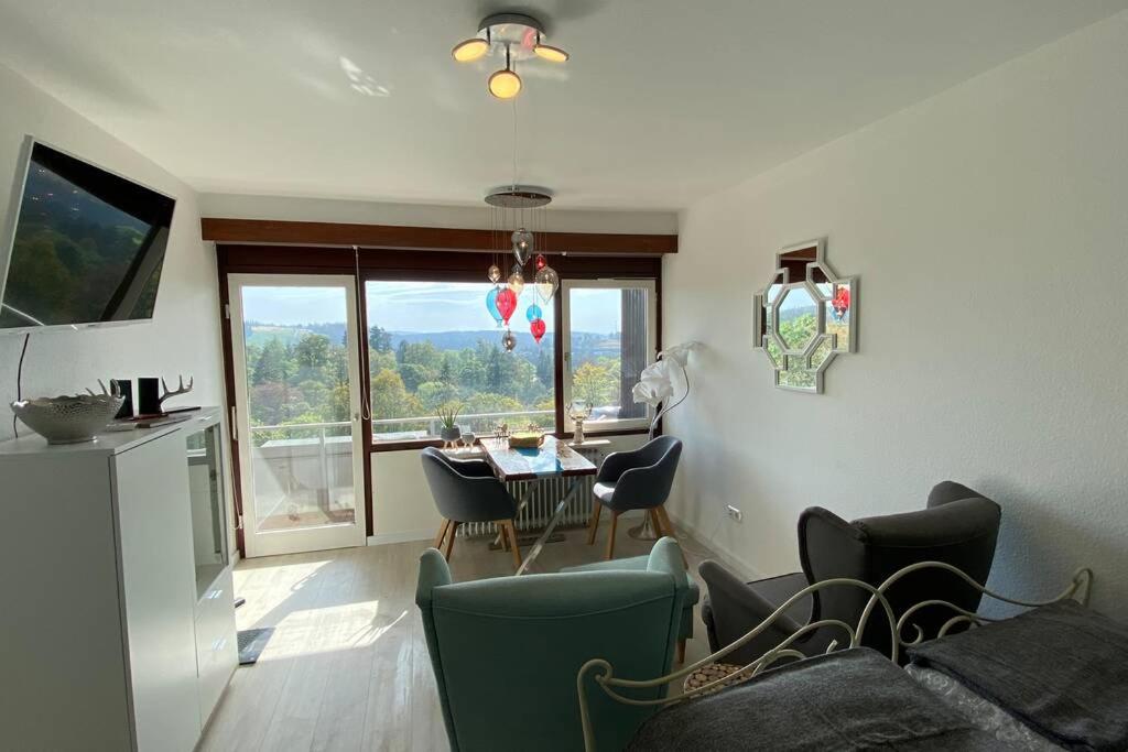 uma sala de estar com uma mesa e cadeiras e uma janela em Apartment Harzblick -NEU MODERNISIERT- em Sankt Andreasberg