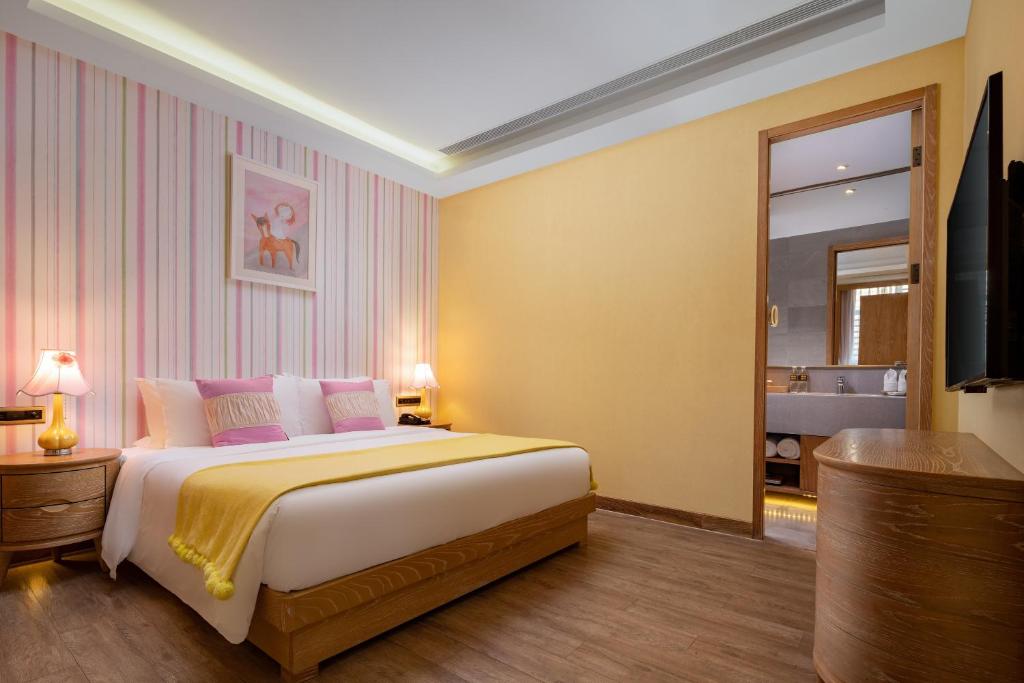 1 dormitorio con 1 cama grande y paredes de color rosa y amarillo en Mangrove Tree Resort World Sanya Bay -Elader Palm Tower, en Sanya
