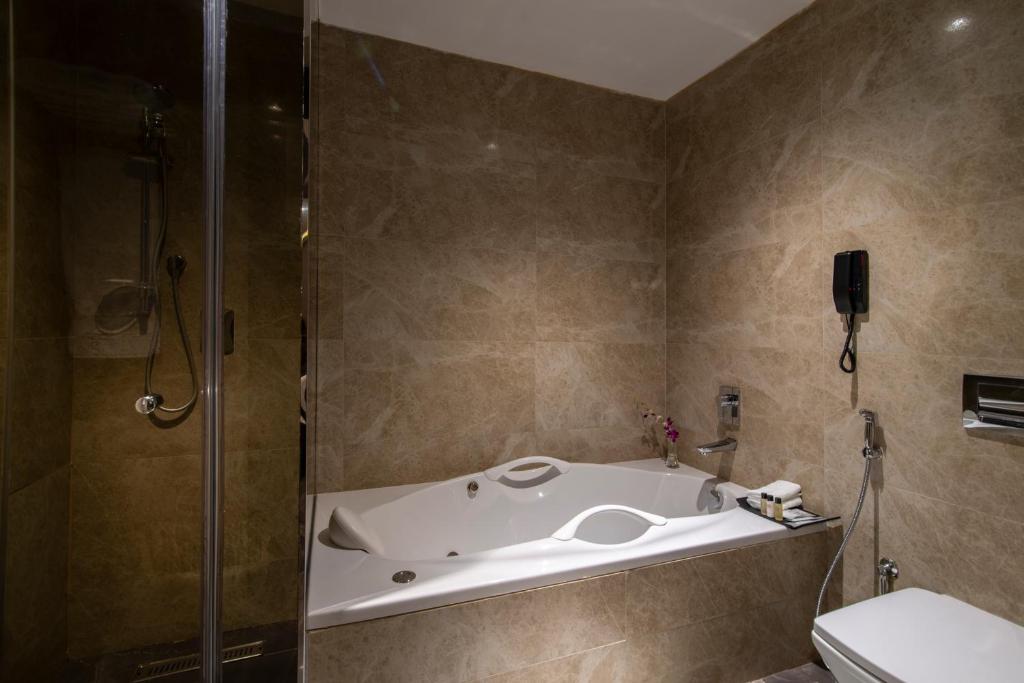 a bathroom with a bath tub and a toilet at Gardino Hotel & Residence in Riyadh