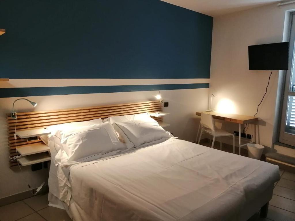 een slaapkamer met een groot wit bed en een blauwe muur bij Albergo della Posta in Mondovì