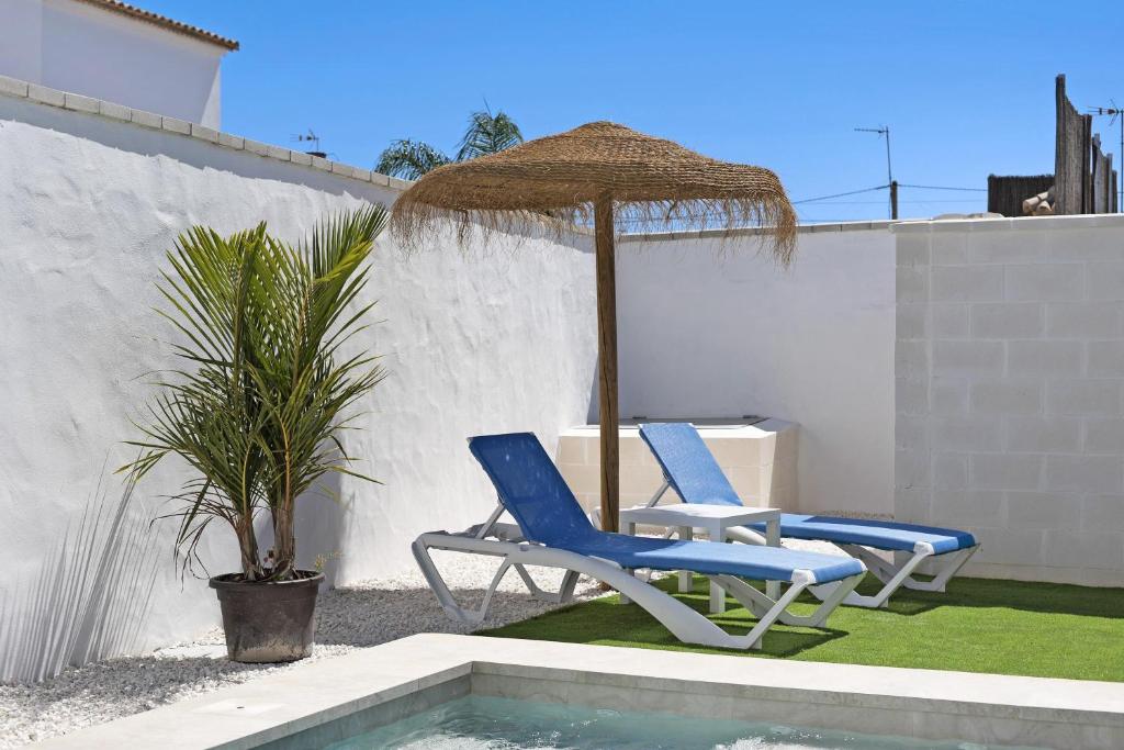 two blue chairs and an umbrella next to a pool at Casa Jaime in Conil de la Frontera
