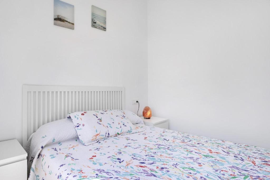 a white bedroom with a bed and two pictures on the wall at Casa Jaime in Conil de la Frontera