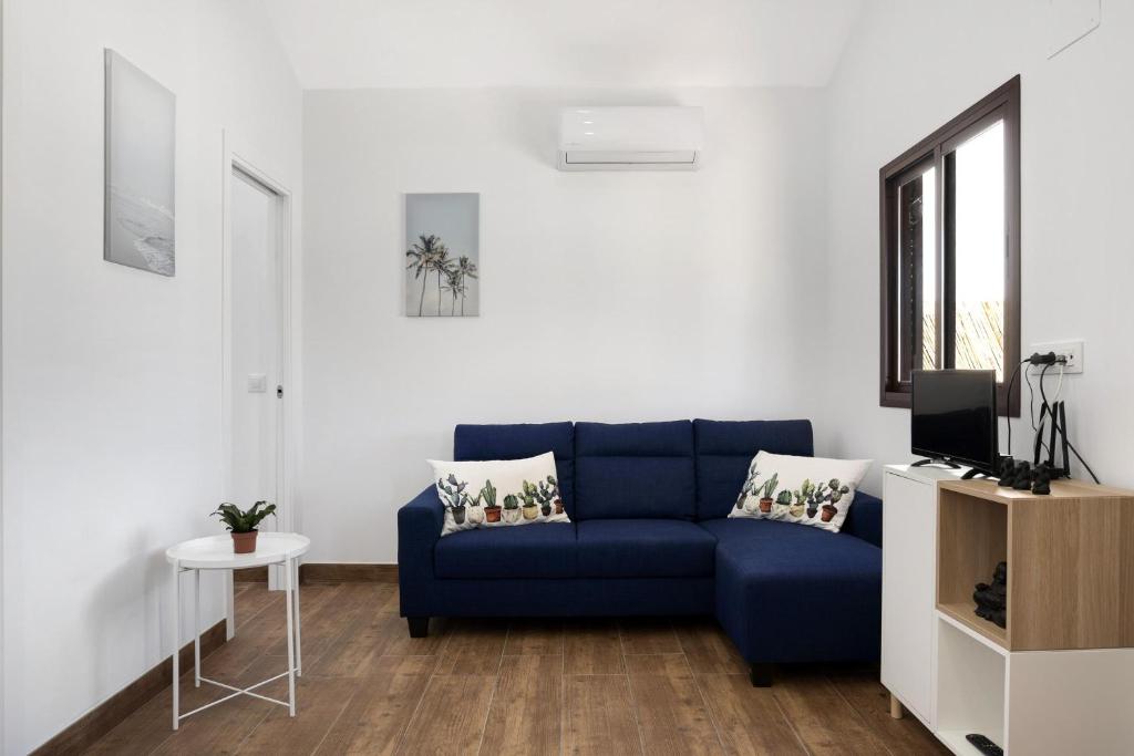 a living room with a blue couch and a tv at Casa Jaime in Conil de la Frontera