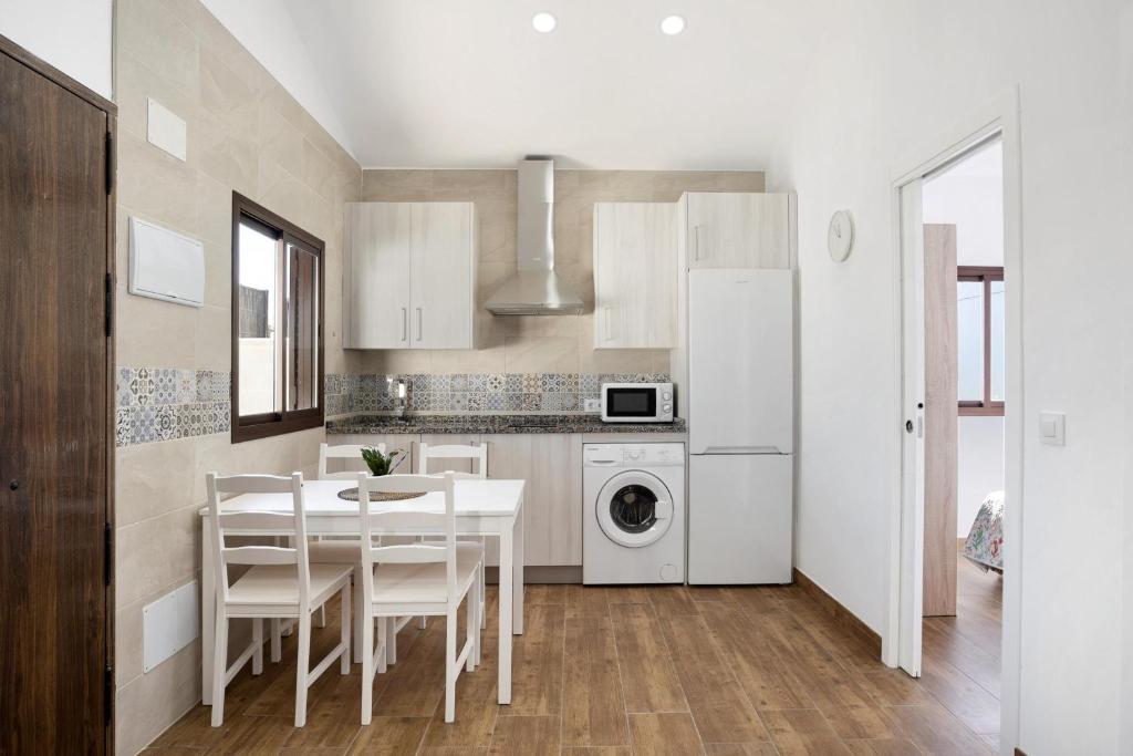 a kitchen with a table and a white refrigerator at Casa Jaime in Conil de la Frontera