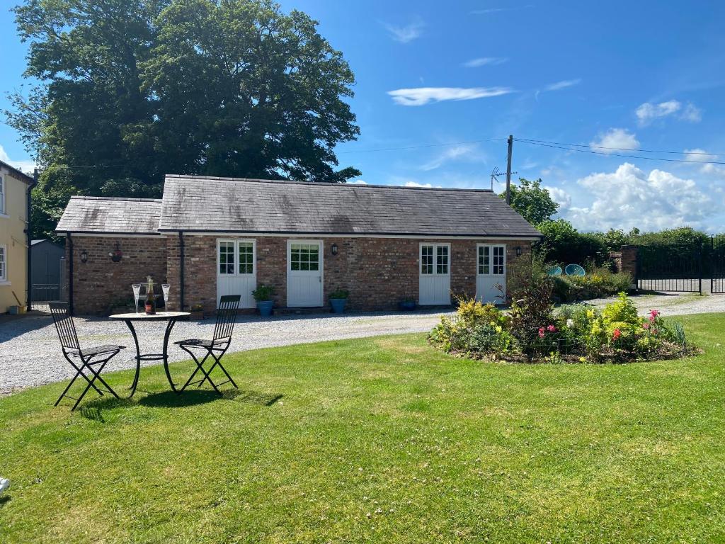 a brick cottage with a table and chairs in the yard at Relaxing Retreat Around Nature in Wrexham