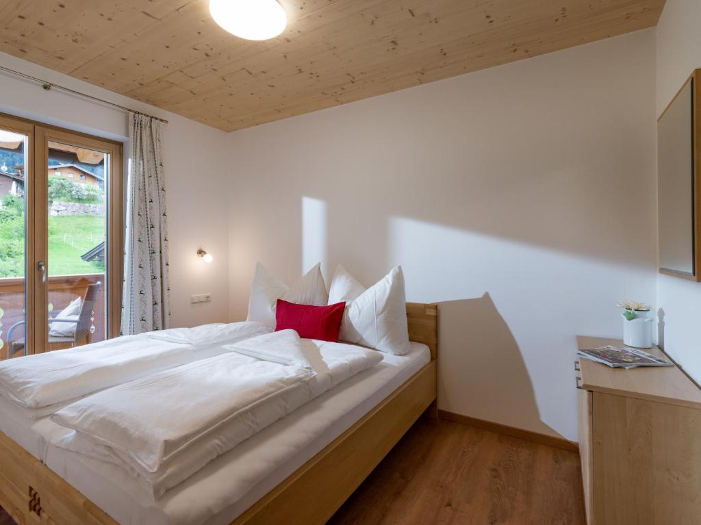 a bedroom with a large white bed with a red pillow at Appartements Bichldorf in Söll