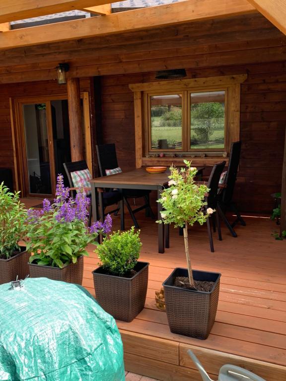 a wooden deck with three potted plants and a table at Ferienhaus Vulkaneifel Bei Hepp in Schönbach